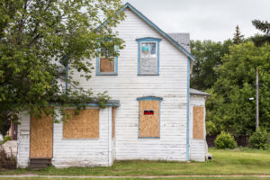 A white house, boarded up and condemned.