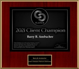 A framed award certificate labeled "Client Champion 2021 Award" presented to Attorney Barry B. Ansbacher, with a black background and gold text, adorned with a circular platinum emblem in the center