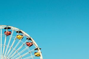 A segment of a Ferris wheel with colorful cabins against a clear blue sky, untouched by recent theme park accidents.