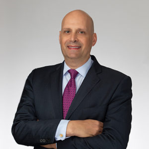 A professional portrait of Barry B. Ansbacher, a Certified Mediator for the Florida Middle District Court, wearing a dark suit, white shirt, and pink tie, smiling with arms crossed against a