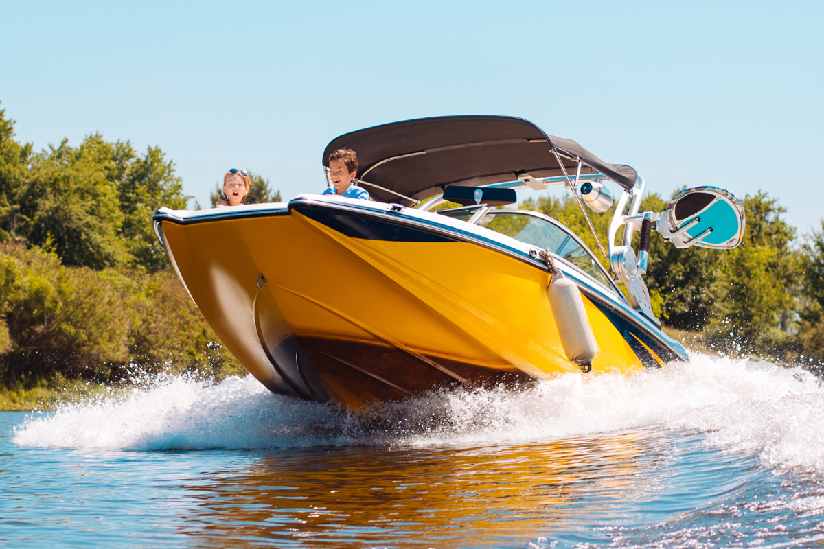 A yellow speedboat with a blue and white interior, carrying three people, speeds across a sunlit lake, creating a spray of water, observed by boat accident lawyers.