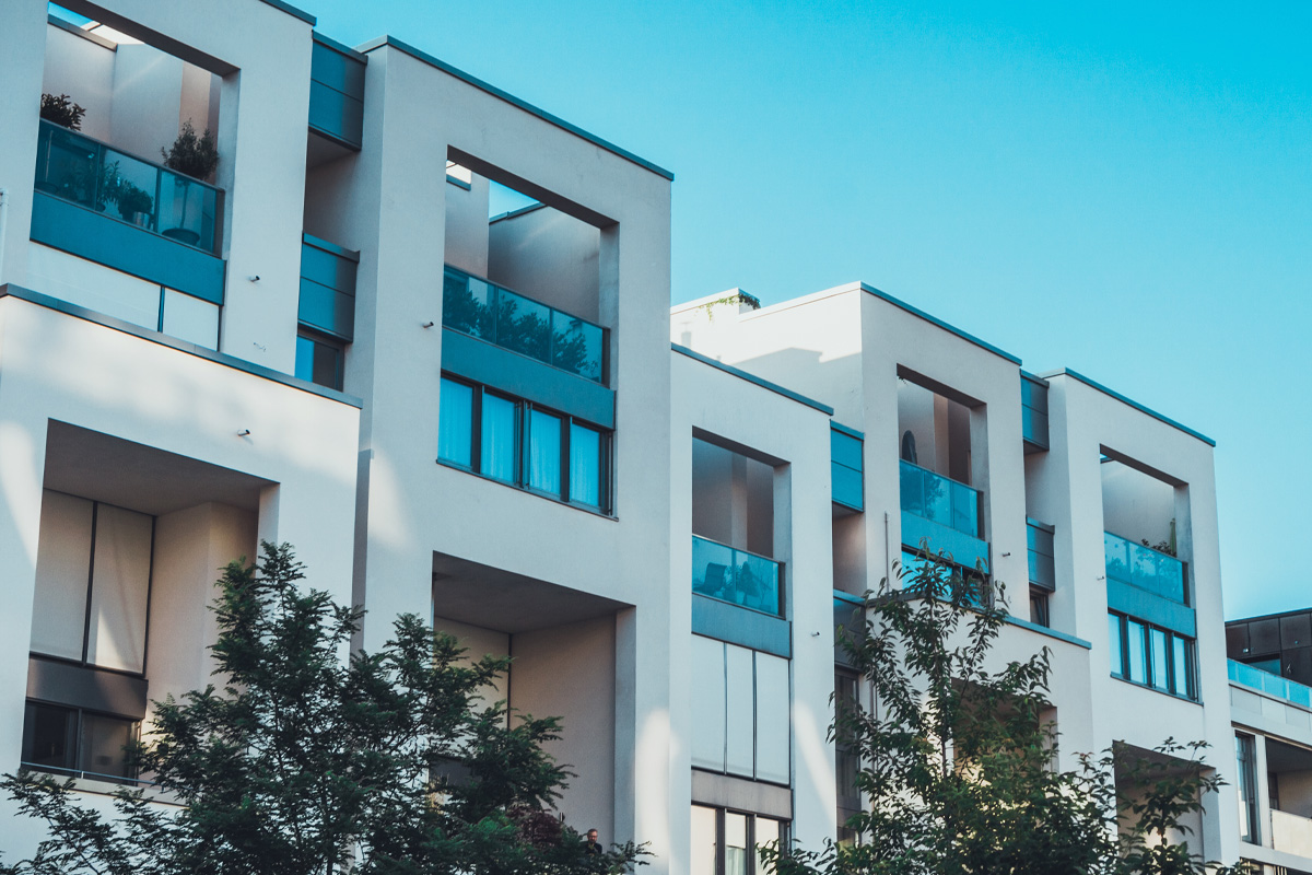 Modern condo building with cubic design elements, large windows, and balconies, under a clear blue sky.