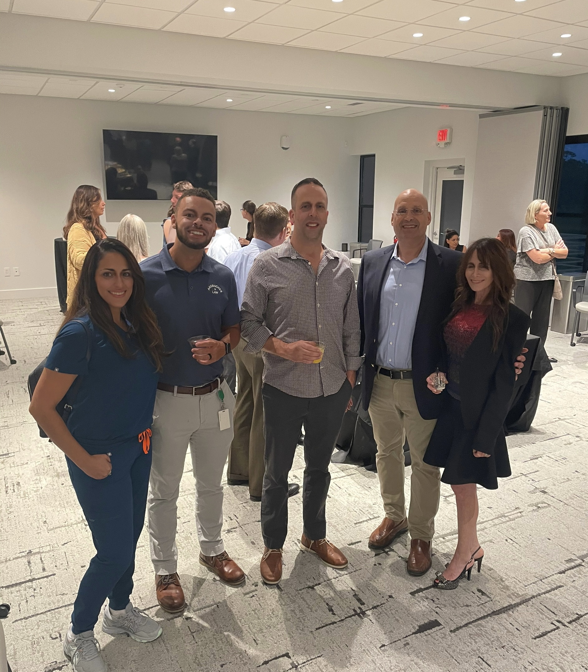 Five professionals posing together at the Grand Opening of the Betty Griffin Center, with two women and three men smiling at the camera.