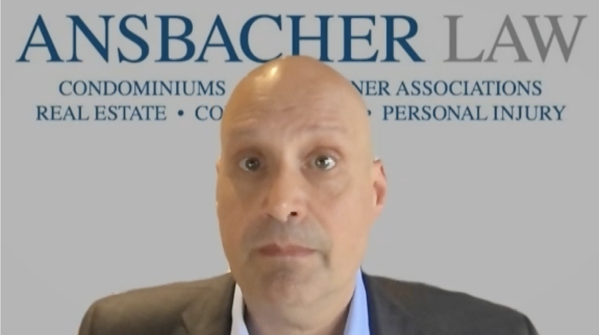 A bald man with a surprised expression stands in front of a banner reading "Ansbacher Law" highlighting specialties in condominiums, homeowner associations, real estate, and personal injury. Attorney Barry Ansb
