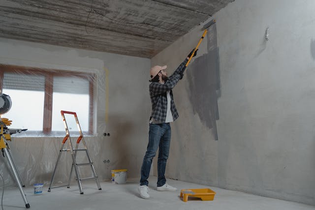 man painting house under construction