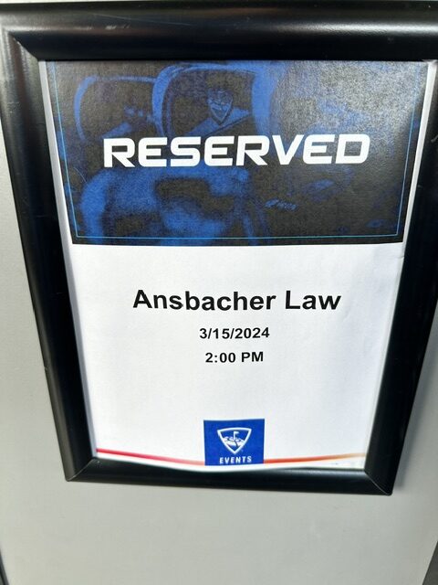 A parking sign labeled "reserved" with "Ansbacher team outing" printed below, indicating a reservation for March 15, 2024, at 2:00 pm, attached to a
