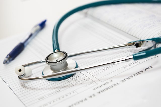 A blue stethoscope and a pen rest on top of a medical form or patient chart, ready to record details from medical appointments or notes taken after an injury.