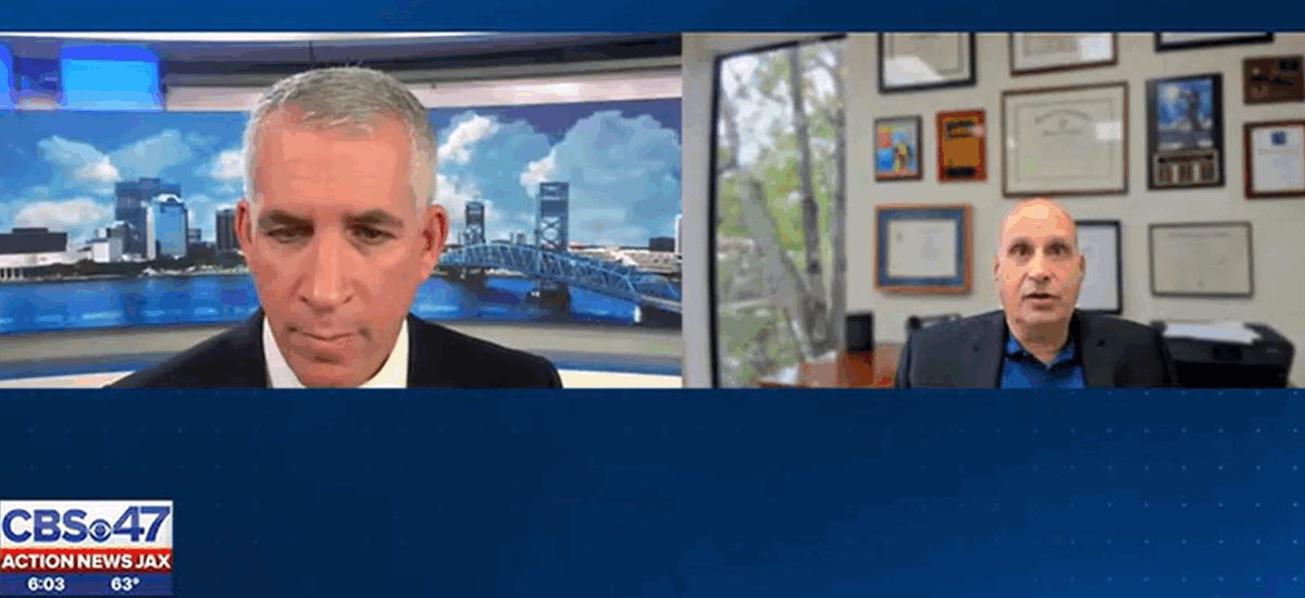 Two men appear in a virtual Action News Jax interview. The man on the left sits in a studio with a cityscape backdrop, while Barry Ansbacher on the right is in an office with framed certificates. The CBS-47 logo is displayed on the bottom left.