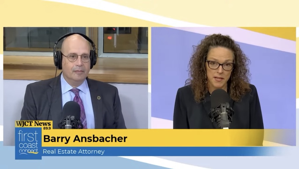 Two people are speaking into microphones in a radio studio. The man on the left wears a suit and headphones, while the woman on the right has glasses and curly hair. On-screen text identifies them and the show as "First Coast Connect.